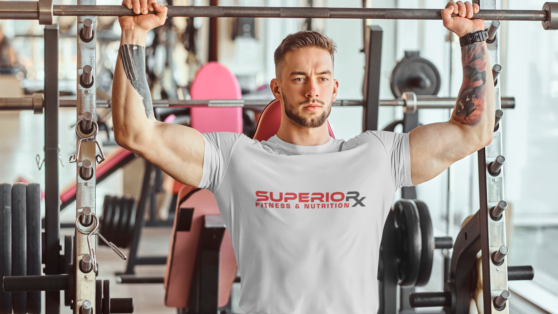 Man lifting weights in a gym wearing a 'Superior RX' t-shirt.